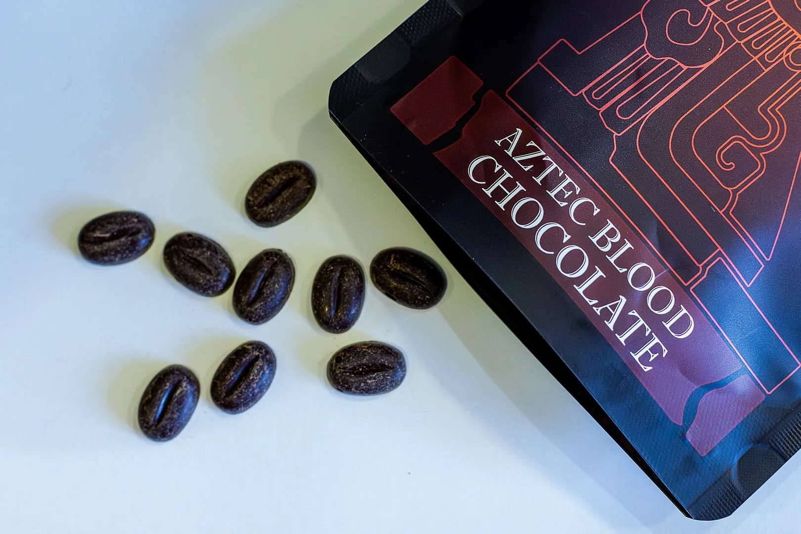 AztecBlood chocolate pieces shaped like cacao beans next to the pouch